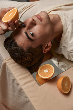 Handsome man close-up oranges mirror attractive lookの写真素材