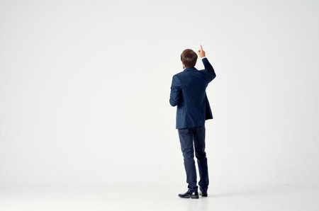 Gentleman in a blue suit gestures with his hands on a light background back view business financeの写真素材