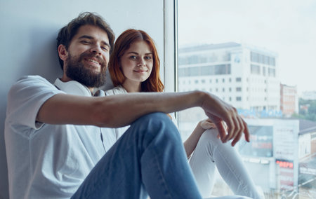 young couple sitting on the windowsill near the window rest fun lifestyleの写真素材