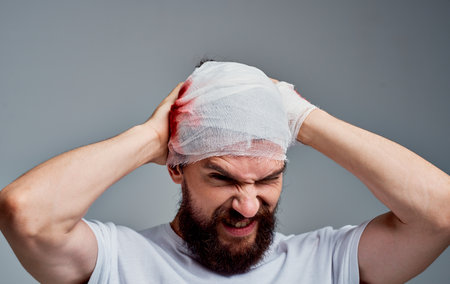 a man in intensive care bandaged head blood on his arm concussion
