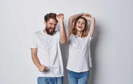 cheerful man and woman in headphones listening to music and dancing on gray background cropped viewの写真素材