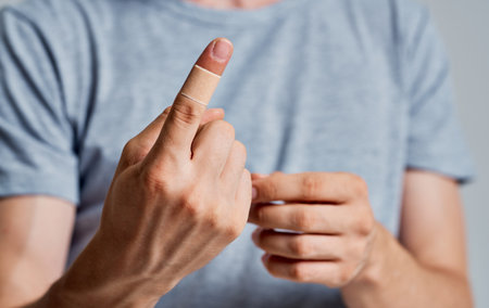 man with germicidal plaster on finger gray t-shirt isolated backgroundの写真素材