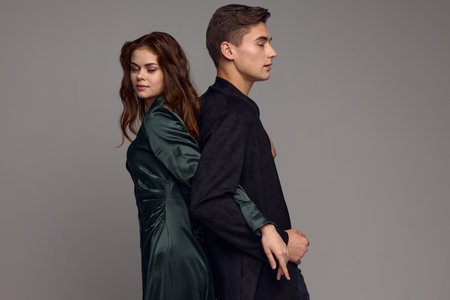 Enamored man and woman in evening suits stand with their backs to each other on gray background cropped viewの写真素材