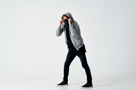 male hacker in a gray sweater stealing black mask on his face