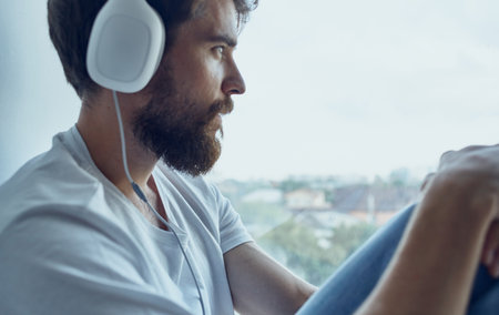 bearded man in headphones music rest interior near windowの写真素材