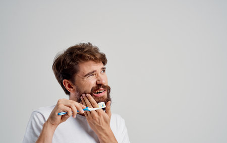 toothache man with beard light background t-shirt model oral cavity careの写真素材