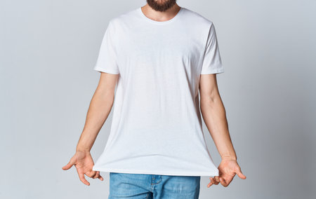 A man in a white T-shirt on a light background gestures with his hands cropped view of jeans Copy Spaceの写真素材