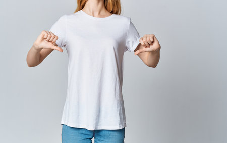 Woman in white t-shirt and jeans gestures with hands cropped view of the modelの写真素材