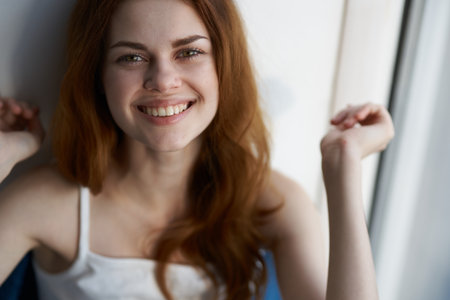 woman sitting on the windowsill near the window smile lifestyle interiorの写真素材