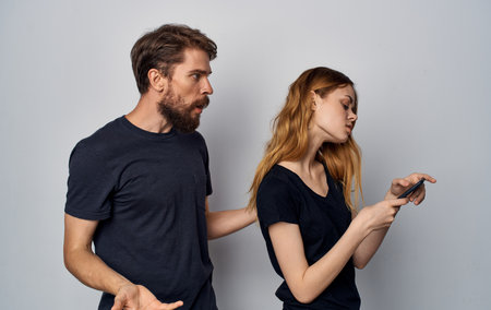 young couple with phone in hands dissatisfaction with technologyの写真素材