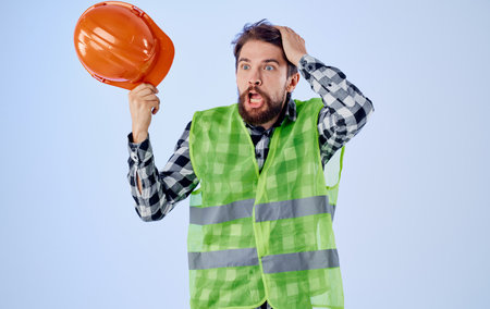 Builder with orange hard hat in hand and reflective vest blue background Copy Spaceの写真素材