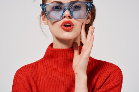 fashionable woman model in a red sweater and blue glasses on a light background emotions cropped viewの写真素材