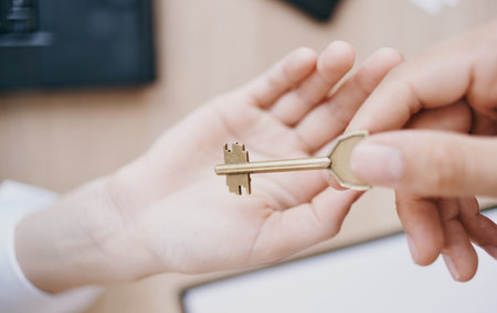 handing the key from hand to hand in the office business finance work documents deskの写真素材