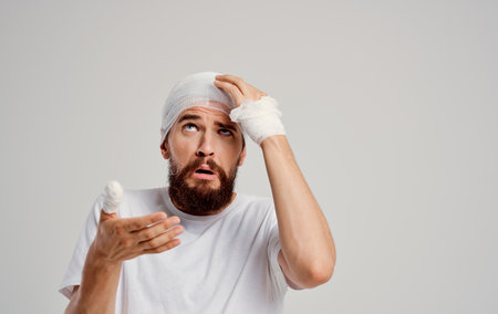 man in white t-shirt bandaged head health problems injury treatmentの写真素材