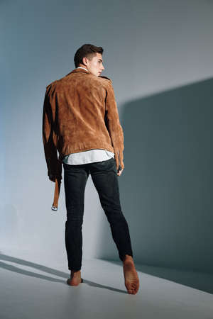 A handsome guy in a jacket stands on the floor with a datum in a damp room