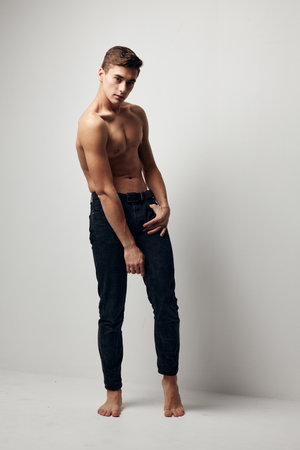 A sexy guy with pumped up arm muscles on a light background in full growthの写真素材