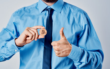 Business man in a blue shirt with a coin in his hand cryptocurrency Bitcoin finance model