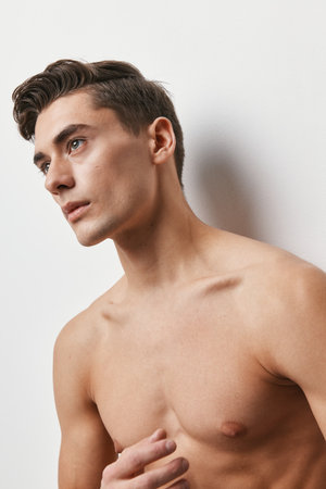 A man with a naked torso is looking forward on a light backgroundの写真素材