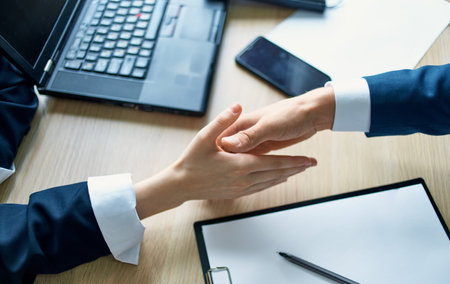 employees shaking hands at work in the office agreement document laptopの写真素材