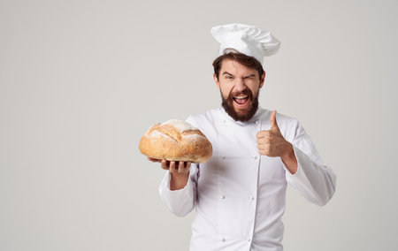 Cropped view of a professional chef with a prepared loaf of bread in hand on a light backgroundの写真素材
