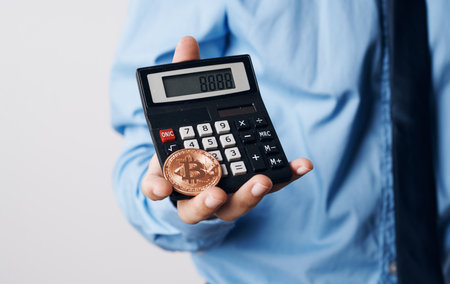 A man holds in his hands a Bitcoin cryptocurrency price increase calculator financial technologyの写真素材