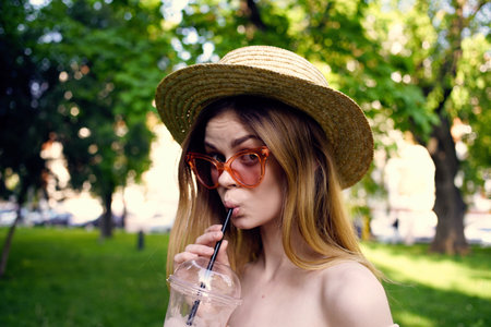 Pretty woman in a hat in the park outdoors glass with a drink Summer dayの写真素材