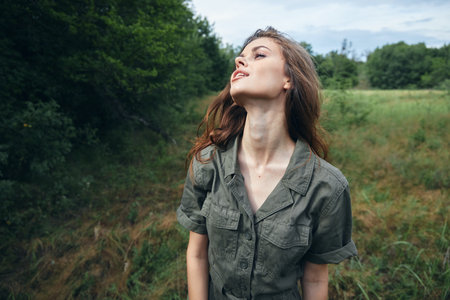 Woman on nature in green jumpsuit looking up landscape green leavesの写真素材
