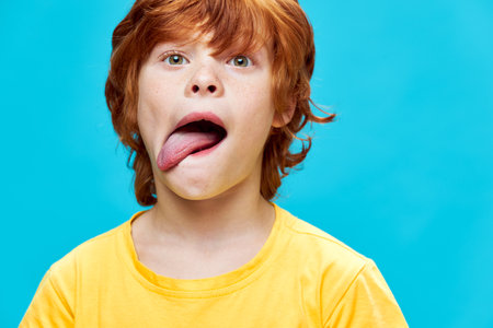 portrait of a redhead boy sticking out tongue close-up yellow t-shirtの写真素材