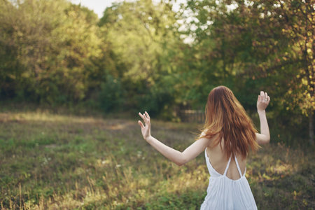 happy women in a sundress runs on green grass in the meadow and trees In the backgroundの写真素材
