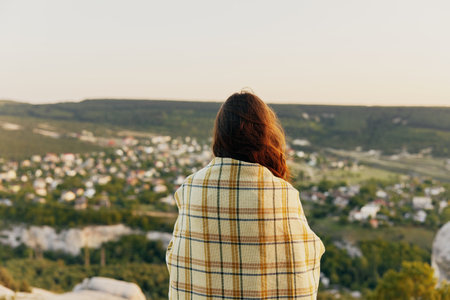 beautiful woman with plaid looks at nature mountains back viewの写真素材