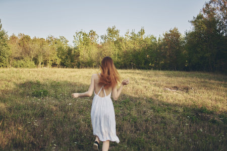 happy journey in a white sundress running on the grass in natureの写真素材
