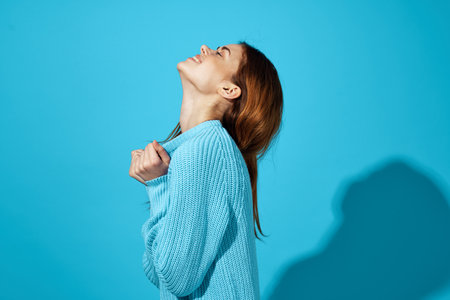 beautiful woman in blue sweater emotions charm attractive look blue backgroundの写真素材