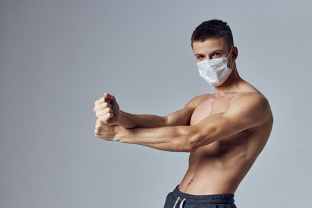 sporty man with muscular body medical mask posing gymの写真素材