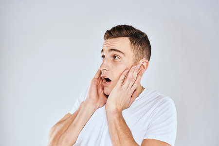 Nice man in a white t-shirt gestures with his hands emotions surprise studioの写真素材