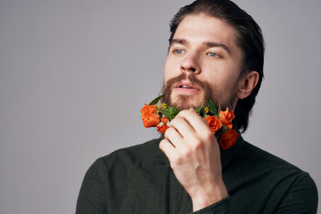 Cute elegant man in a black shirt flowers in a beard decoration romance gray backgroundの写真素材
