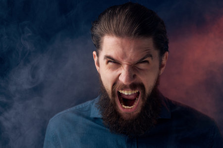 Emotional bearded man angry look shirt smoke in the backgroundの写真素材