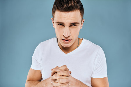 emotional displeased man cropped view white t-shirt blue backgroundの写真素材