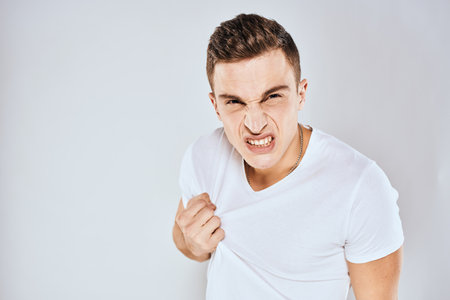 Man in white t-shirt displeased facial expression gesturing with hands studio lifestyle