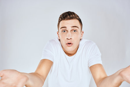 Nice man in a white t-shirt gestures with his hands emotions surprise studioの写真素材