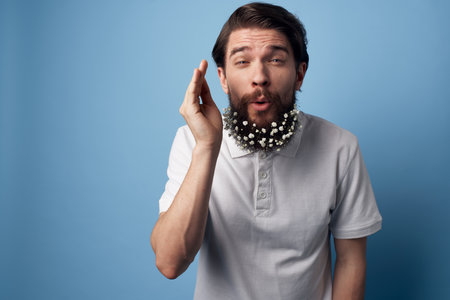 Man in white shirt beard with flowers decorating blue backgroundの写真素材