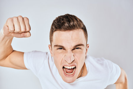 Man in white t-shirt displeased facial expression gesturing with hands studio lifestyleの写真素材