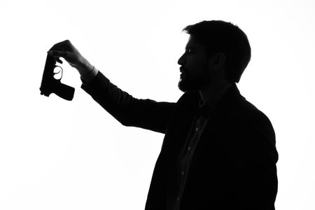 shadow of a man with a gun in his hands aiming suicide danger