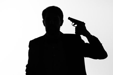 shadow of a man with a gun in his hands aiming suicide dangerの写真素材