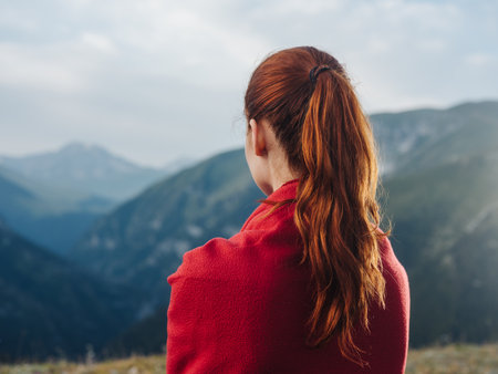 woman traveler with a red plaid on her shoulders in the mountainsの写真素材
