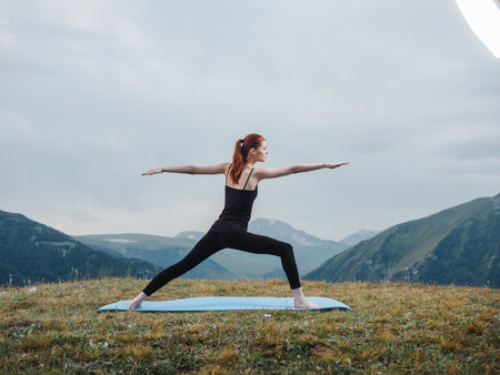 Woman practices yoga on a rug outdoors in the mountains fresh air tourismの写真素材
