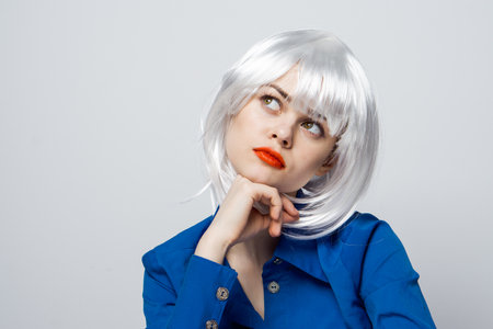 pretty woman holding hands near face white wig red lips close-up blue shirtの写真素材