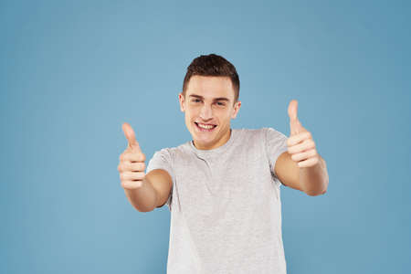 cheerful man in a white t-shirt gesturing with his hands emotions blue background