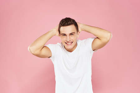 Cheerful handsome man in white t-shirt emotions pink isolated background