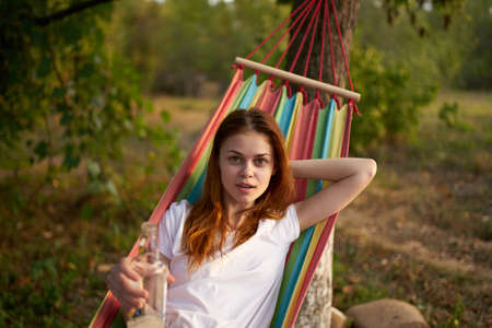 happy woman lies in a hammock outdoors in the forest laughingの写真素材