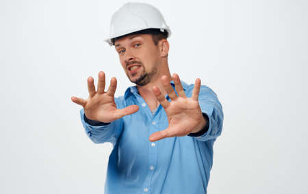 Emotional architect builder in a white helmet and in a blue shirt on an isolated backgroundの写真素材